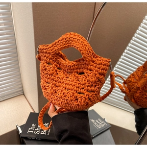 Detail of bright orange handmade crochet mini bag with hollow weave and shoulder strap