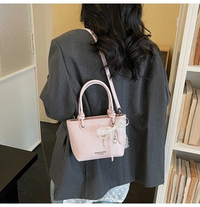 Détail du sac seau rose avec breloque nœud en perles et dentelle et logo MIKAXIQI