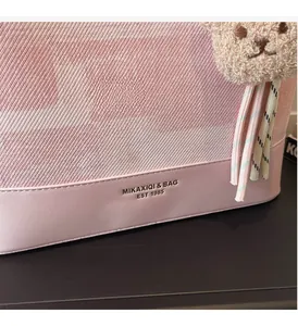 Detail of pink woven fabric and faux leather tote with plush bear charm accessory
