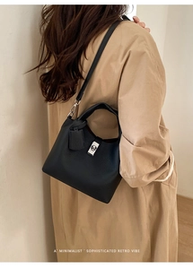 Close-up of black lychee-textured leather bucket bag with silver metal lock detail