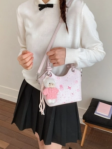 Pink bucket bag with cartoon cat prints and bear plush charm shown on a model