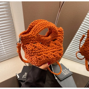 Close-up of bright orange hand-woven mini bag with hollow texture and silver metal clips