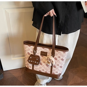 Dettaglio della borsa tote con stampa gatto e manici in pelle marrone con ciondolo