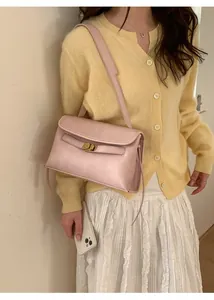 Vue latérale d'un sac à bandoulière en cuir rose pâle avec boucle dorée sur un mannequin