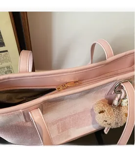 Detail of pink tote bag showing smooth gold zipper closure and plush bear charm accessory