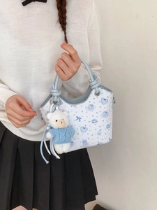 Chic white bucket bag with blue cartoon prints and a cute teddy bear plush charm