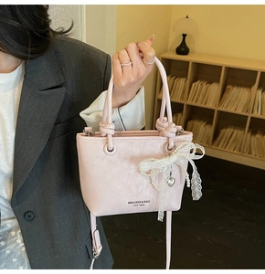Détail du sac seau rose avec breloque en dentelle et perles et poignées nouées