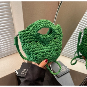 Close-up of emerald green woven handbag showing textured hollow knit craftsmanship