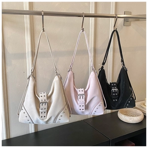 Detailed view of three stud-decorated hobo tote bags in beige, pink, and black colors