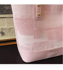 Detail of pink twill jacquard fabric and leather stitching on large tote bag with rivets