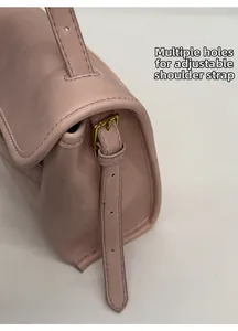 Détail de la bandoulière réglable avec boucle en métal doré sur le sac en cuir rose mat