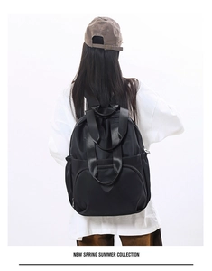 Rear view of a model wearing a large capacity black travel backpack with multiple pockets