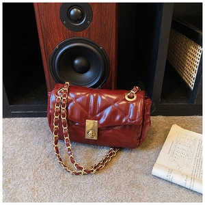 Detailed view of glossy burgundy quilted chain bag with gold square twist lock