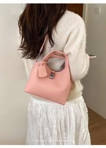 Detail of pink lychee leather bucket bag with silver turn-lock clasp and shoulder strap