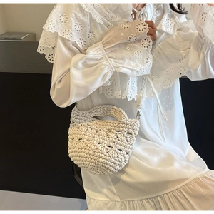 Detail of hand-woven cream mini crossbody bag with textured crochet patterns and top handle