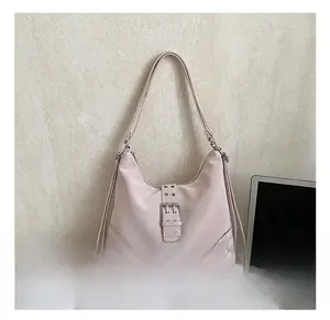 Detailed view of light pink tote bag featuring metallic rivets and buckle hardware