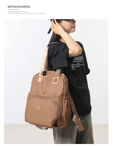 Close-up of brown nylon travel backpack with large front zipper pocket and side drawstring