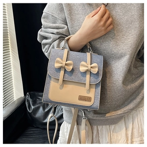 Detailed view of blue denim and cream leather patchwork backpack with bow accents