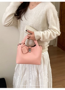 Detail of light pink pebble leather handbag with silver twist lock and minimalist design