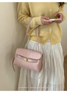 Détail du sac bandoulière rose clair avec fermoir doré et design rétro minimaliste