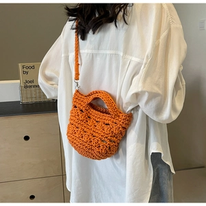 Detail view of handmade orange woven crochet bag with hollow mesh texture and shoulder strap