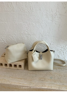 Detail of cream bucket bag and pouch set featuring textured lychee pattern leather
