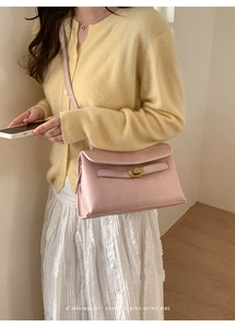 Détail d'un sac Kelly rétro en cuir rose pâle avec fermoir tournant doré porté par un mannequin