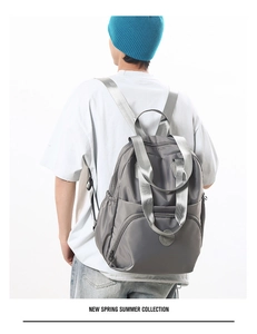 Detail showing the gray multi-functional travel backpack on a male model with padded straps