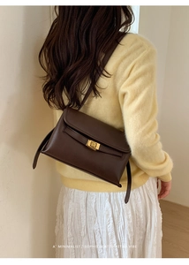 Détail d'un sac bandoulière rétro marron foncé avec boucle dorée porté par un mannequin