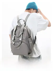 Detail view of large grey waterproof backpack showing zippers and side pockets on model