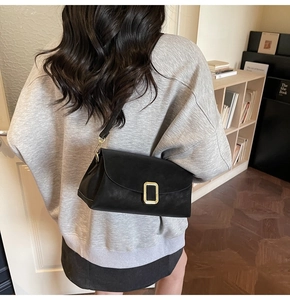 Gros plan sur le sac bandoulière noir mat avec une boucle magnétique en métal doré