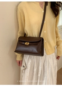 Détail d'un sac bandoulière vintage en cuir marron foncé avec fermoir en métal doré