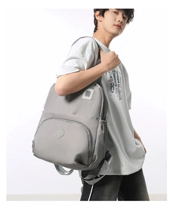 Detailed close-up of a men's gray waterproof nylon backpack with branded front zip pocket