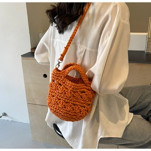 Detail view of orange crochet knit bucket bag showing intricate woven texture and strap