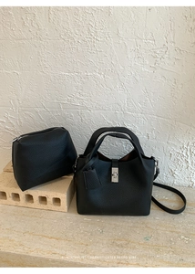 Detail of black lychee grain leather bucket bag set with silver clasp and small pouch