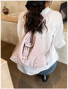Pink rivet backpack featuring large buckle straps and metal eyelets on soft matte faux leather