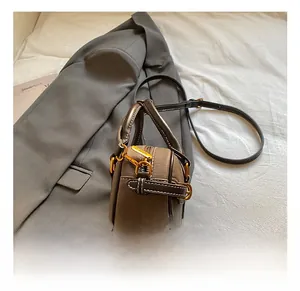 Detailaufnahme der kleinen Kontrasttasche mit goldenen Beschlägen und feinen Nähten