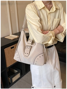Close-up of off-white faux leather tote with silver rivets and metal buckle details