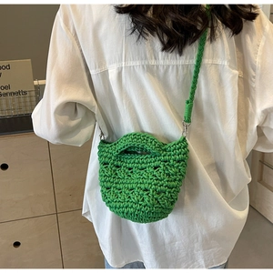 Detail of green crochet crossbody bag showing woven texture and silver metal hardware