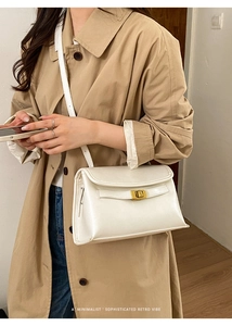 Gros plan du sac en cuir blanc avec fermoir doré sur un trench-coat de couleur kaki