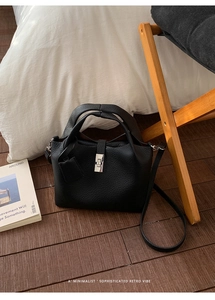 Detail of black pebbled leather bucket bag with silver rotating clasp and long shoulder strap