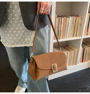 Vue détaillée du sac bandoulière marron rétro avec une grande boucle en métal doré