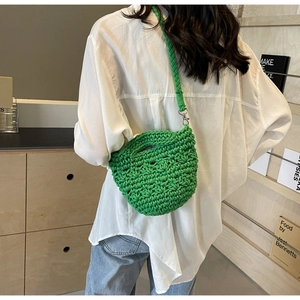 Detail of hand-woven bright green hollow-out shoulder bag with bold texture and metal hooks