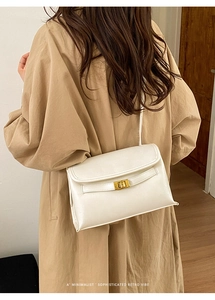 Détail d'un sac bandoulière blanc crème avec fermoir doré porté par un mannequin de dos