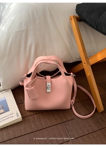 Detail of pink lychee leather bucket bag featuring silver twist lock and shoulder strap