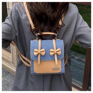 Detailed view of blue denim and brown leather mini backpack with bow accents