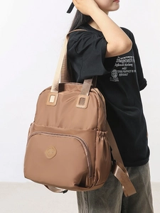 Brown nylon multi-functional backpack with large capacity and side pockets shown on model