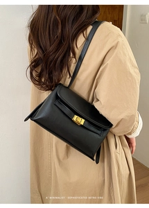 Détail du sac à bandoulière en similicuir noir avec une boucle dorée élégante sur femme