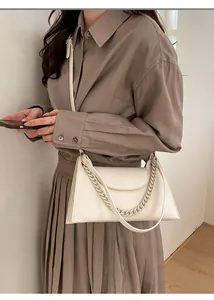 Chic cream-white textured leather crossbody bag styled on a model in a brown dress