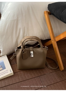 Detail of lychee textured leather bucket bag with silver turn-lock in a home setting